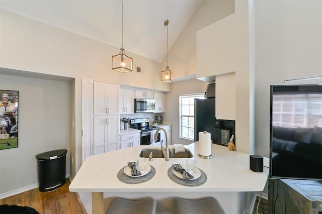 kitchen featuring a peninsula, a sink, visible vents, appliances with stainless steel finishes, and a breakfast bar area