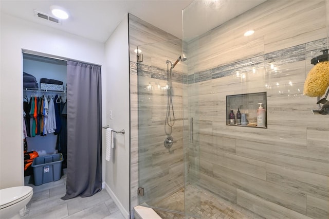 full bath with a walk in closet, toilet, visible vents, and a stall shower