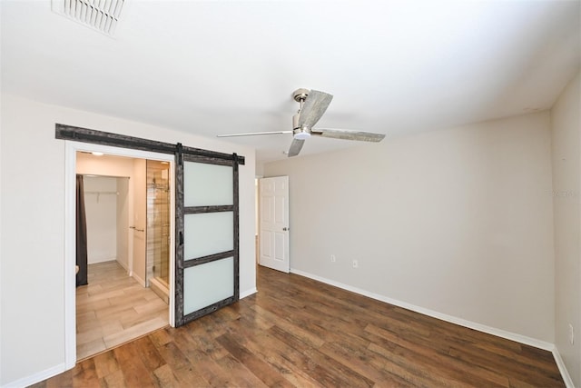 9730 Lake Chase Island Way Unit 9730, Tampa, FL 33626 - unfurnished bedroom featuring a barn door, dark wood-style floors, a spacious closet, and ceiling fan