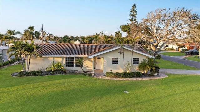 view of front of property with a tiled roof, a chimney, a front lawn, and stucco siding