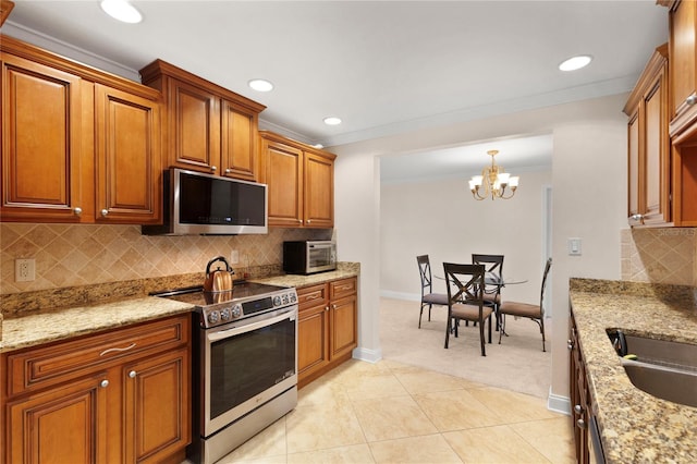 kitchen with brown cabinets, light tile patterned floors, backsplash, appliances with stainless steel finishes, and ornamental molding