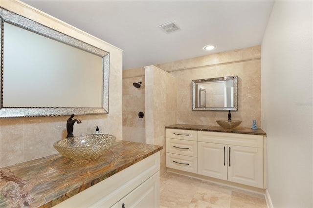 full bathroom featuring visible vents, tile walls, two vanities, and a sink