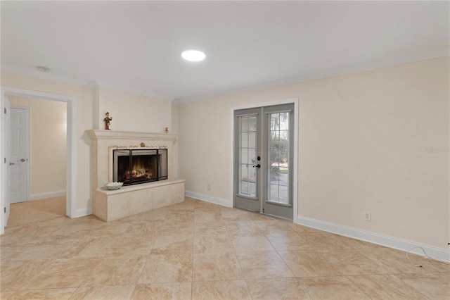 unfurnished living room with french doors, ornamental molding, a premium fireplace, and baseboards