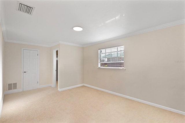 empty room with carpet, visible vents, crown molding, and baseboards