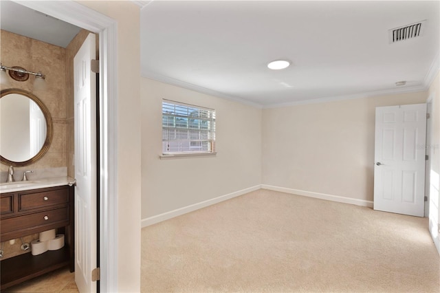 interior space with light carpet, baseboards, visible vents, ornamental molding, and a sink