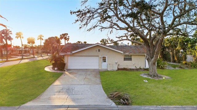 view of front of house featuring concrete driveway, a front yard, a tile roof, and stucco siding