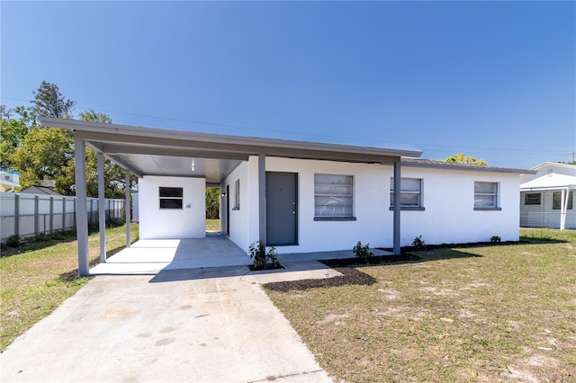 view of front of home with stucco siding, concrete driveway, a front lawn, and fence