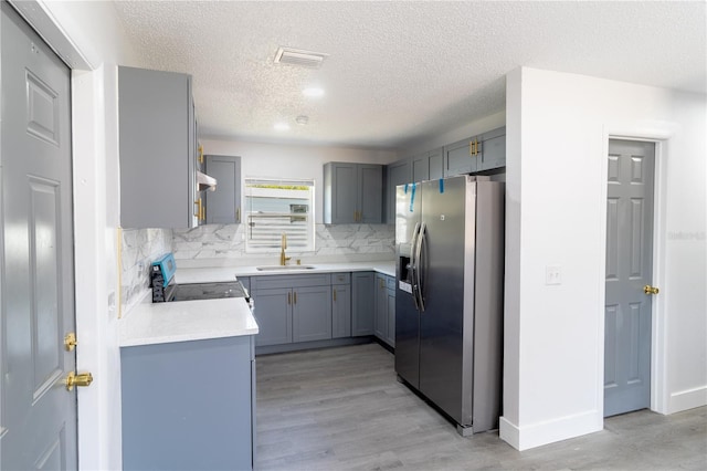 kitchen featuring light wood finished floors, visible vents, stainless steel appliances, and a sink