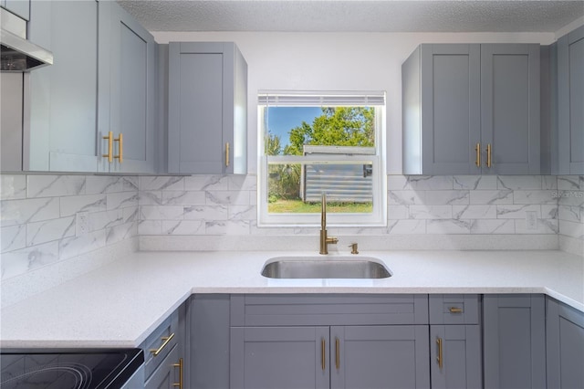 kitchen featuring a sink, extractor fan, light countertops, a textured ceiling, and backsplash