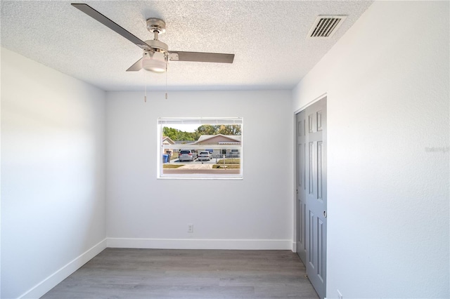 spare room featuring ceiling fan, wood finished floors, visible vents, and baseboards