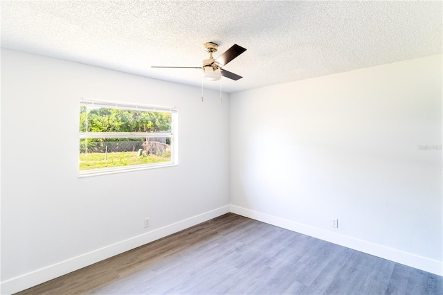 spare room featuring baseboards, a textured ceiling, wood finished floors, and a ceiling fan