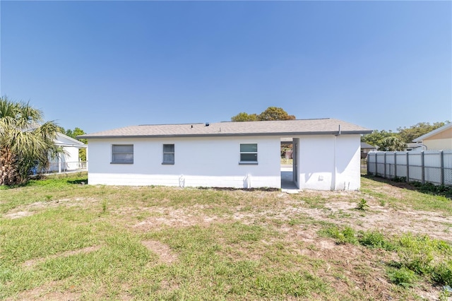 back of property featuring fence, a lawn, and stucco siding