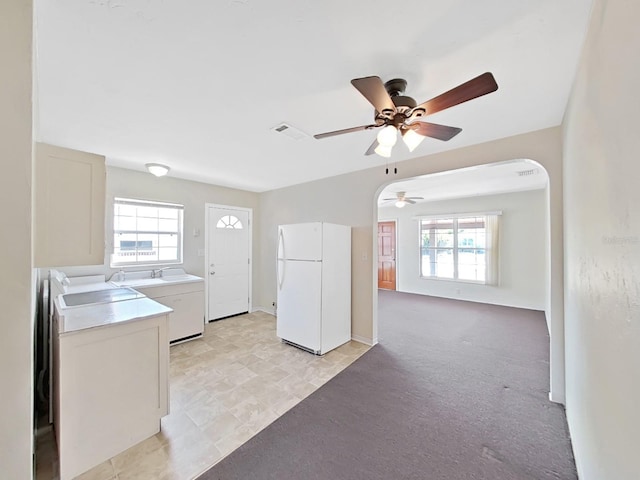 kitchen with light carpet, light countertops, freestanding refrigerator, and a wealth of natural light