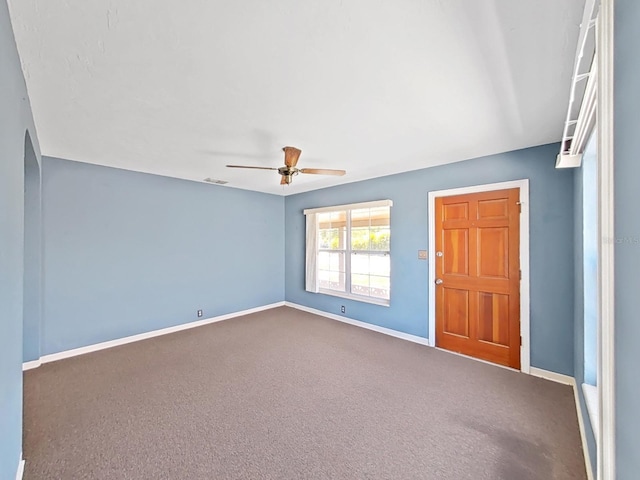 carpeted empty room with visible vents, baseboards, and ceiling fan