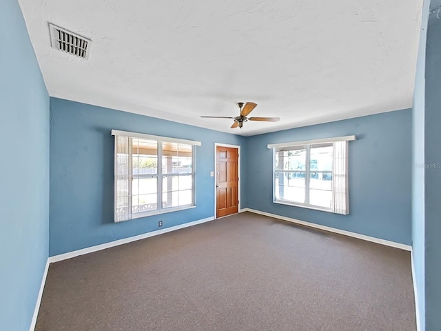 spare room featuring visible vents, baseboards, a healthy amount of sunlight, and a ceiling fan