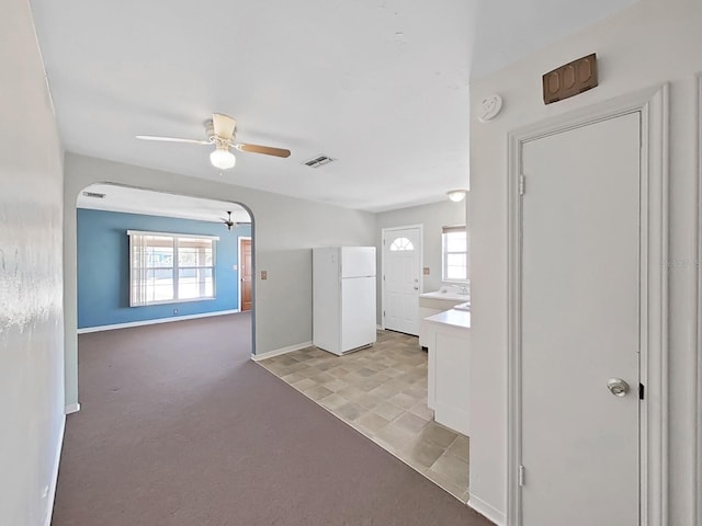 interior space with a wealth of natural light, visible vents, light carpet, and baseboards