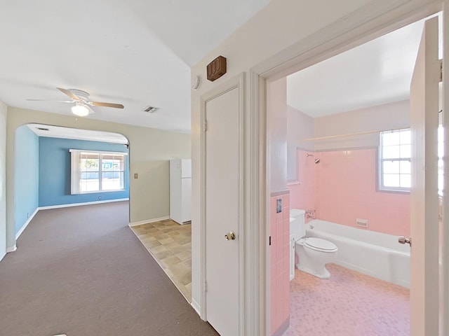 full bathroom with washtub / shower combination, toilet, a healthy amount of sunlight, and visible vents