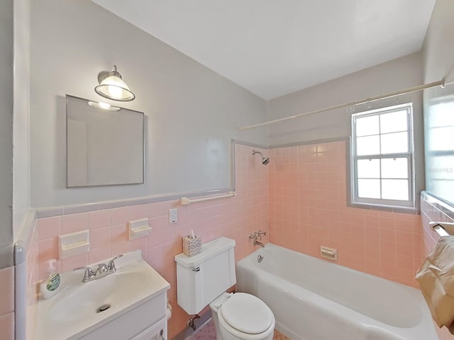 full bath with toilet, tile walls, wainscoting,  shower combination, and vanity