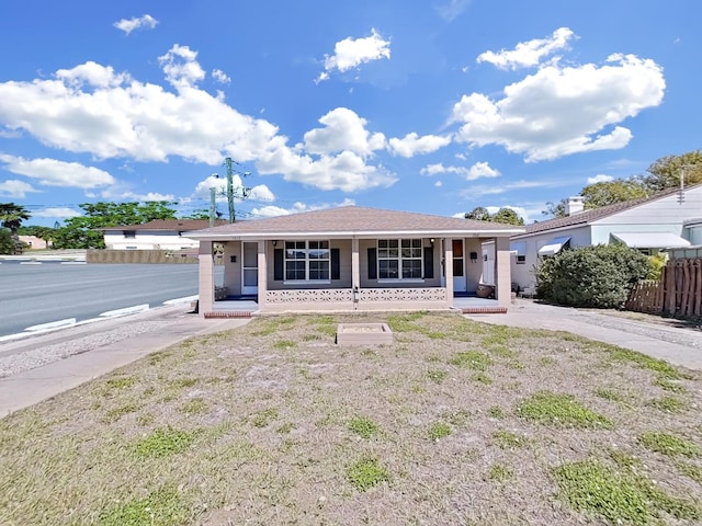 ranch-style home featuring covered porch and fence