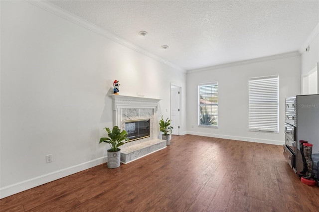 living room featuring hardwood / wood-style flooring, crown molding, a high end fireplace, and a textured ceiling