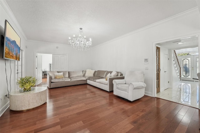 living area featuring ornamental molding, a textured ceiling, an inviting chandelier, and wood-type flooring