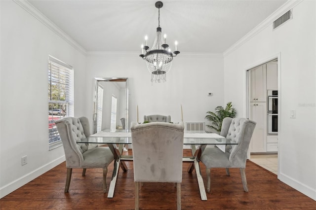 dining area with visible vents, wood finished floors, an inviting chandelier, crown molding, and baseboards