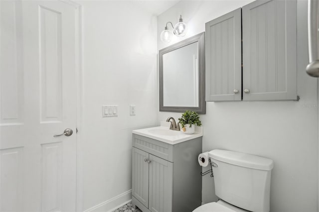 half bath with vanity, toilet, and baseboards