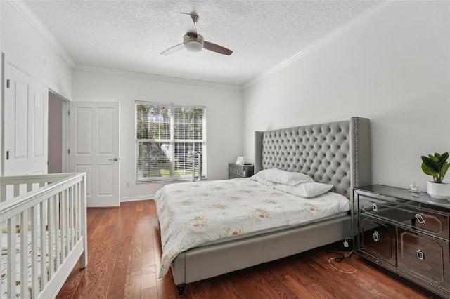 bedroom with dark wood-type flooring, ornamental molding, a ceiling fan, and a textured ceiling