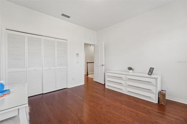 unfurnished bedroom featuring a closet, visible vents, baseboards, and wood finished floors