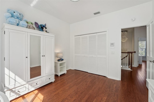 bedroom with dark wood-style floors, visible vents, and baseboards