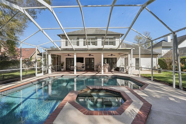 view of swimming pool with glass enclosure, a patio, a ceiling fan, and a pool with connected hot tub