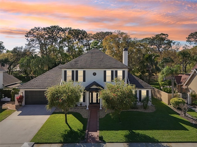 view of front of home featuring fence, driveway, an attached garage, stucco siding, and a front lawn