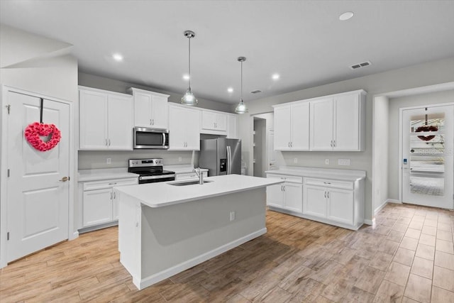 kitchen featuring stainless steel appliances, light countertops, visible vents, light wood-style floors, and a kitchen island with sink