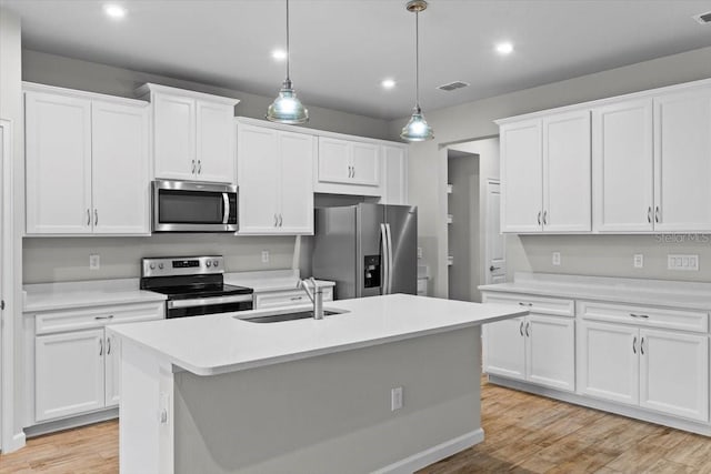 kitchen featuring stainless steel appliances, light countertops, light wood-type flooring, white cabinetry, and a sink