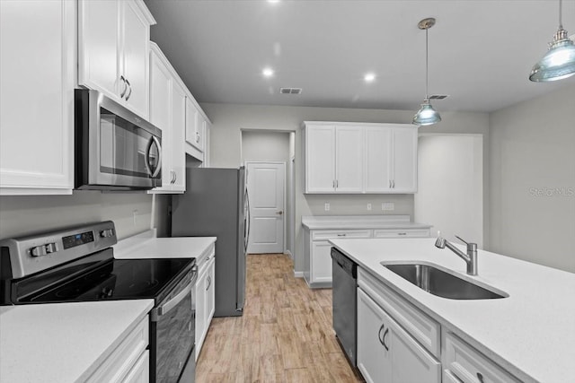 kitchen featuring a sink, white cabinetry, light wood-style floors, light countertops, and appliances with stainless steel finishes