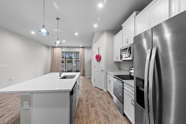 kitchen featuring a sink, light countertops, appliances with stainless steel finishes, light wood finished floors, and a center island with sink