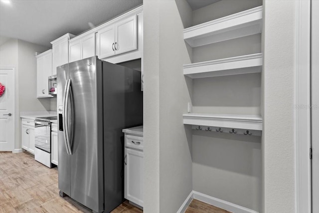 kitchen with stainless steel appliances, light countertops, white cabinetry, and open shelves