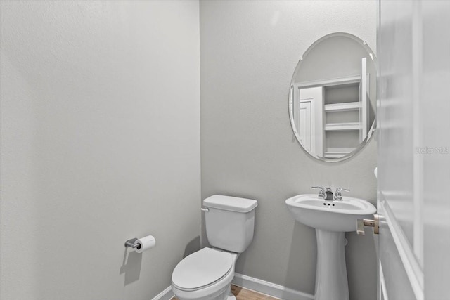 bathroom with baseboards, a sink, and toilet