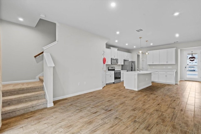 kitchen with stainless steel appliances, light wood-type flooring, open floor plan, and visible vents