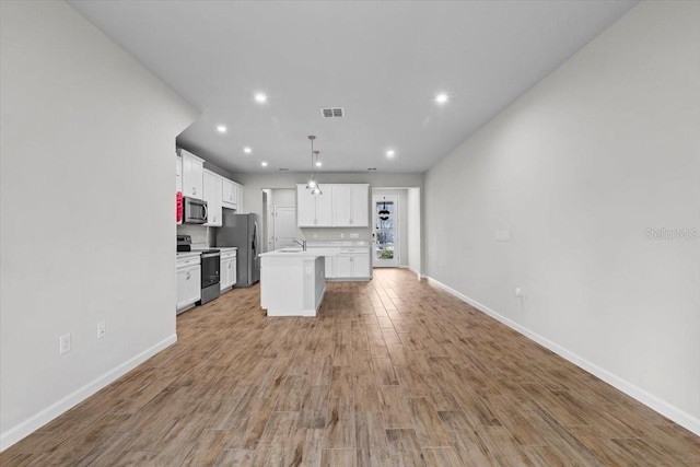 kitchen with a kitchen island with sink, white cabinetry, light wood-style floors, open floor plan, and appliances with stainless steel finishes