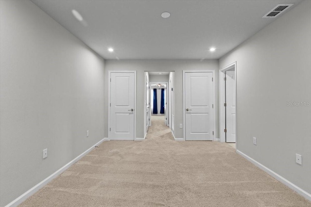 unfurnished room featuring light colored carpet, visible vents, and baseboards