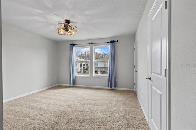 carpeted empty room featuring a textured ceiling and baseboards