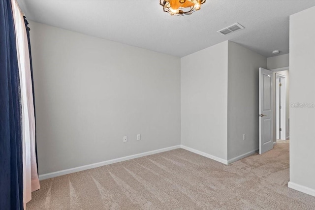 carpeted spare room featuring baseboards, visible vents, and a textured ceiling