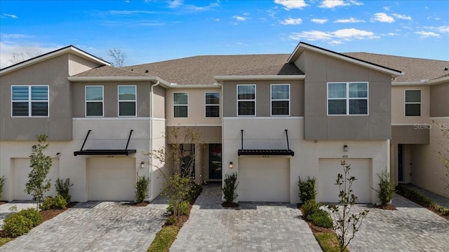 townhome / multi-family property featuring driveway, an attached garage, and stucco siding