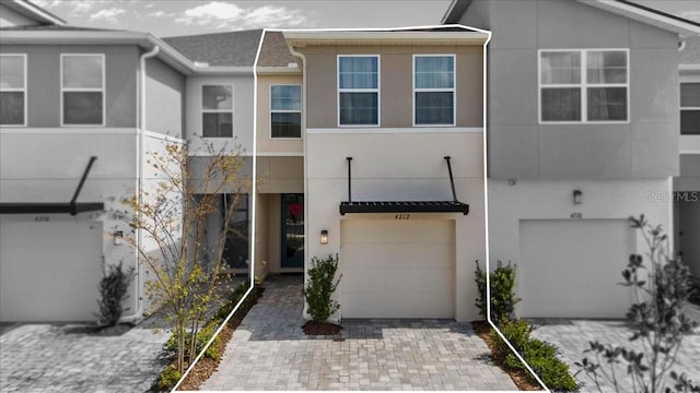 townhome / multi-family property with driveway, a garage, and stucco siding