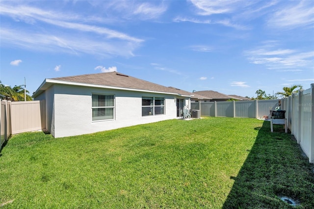 rear view of house featuring stucco siding, a fenced backyard, and a yard