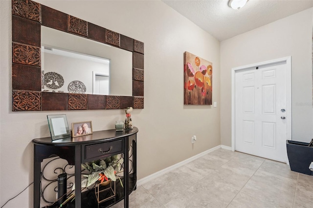 foyer entrance featuring baseboards and a textured ceiling