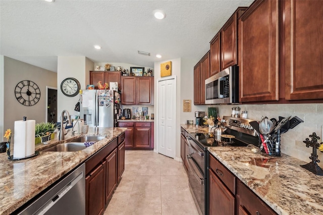 kitchen with light stone countertops, tasteful backsplash, stainless steel appliances, and a sink