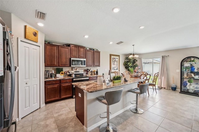 kitchen featuring appliances with stainless steel finishes, a breakfast bar, visible vents, and light tile patterned flooring