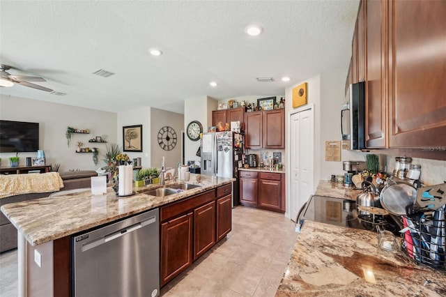 kitchen with visible vents, light stone counters, appliances with stainless steel finishes, open floor plan, and a sink